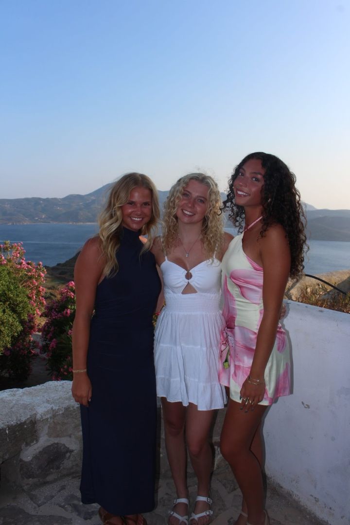 Natalie and friends pose on a stone balcony overlooking the sea