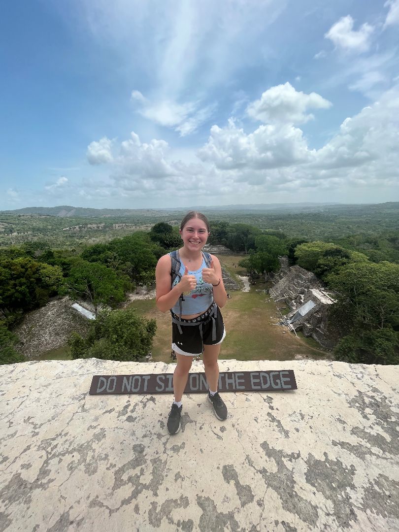 Cordelia standing atop a Mayan ruin giving a thumbs up
