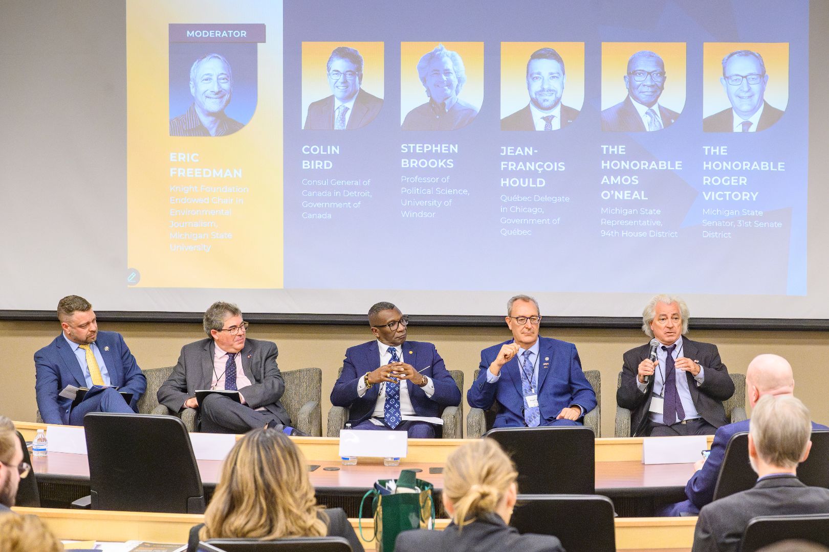 Panelists seated and speaking at the front of the room