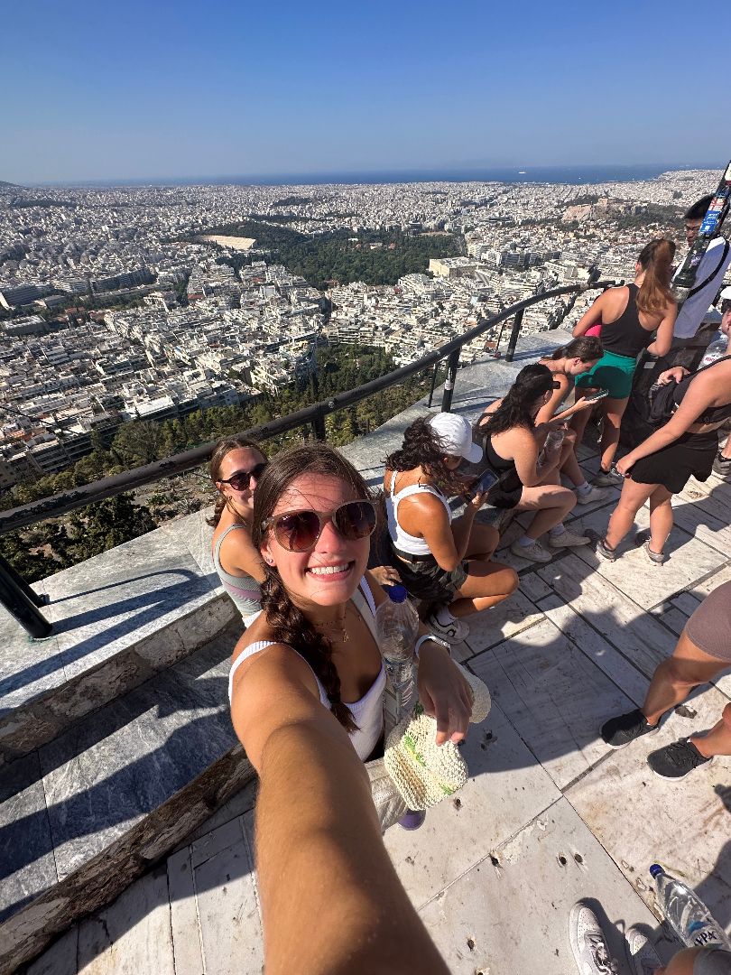 Alyssa taking a selfie up on a mountain overlooking a town in Greece