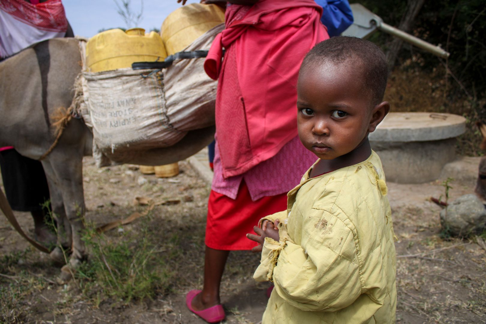 Kenyan child in yellow shirt looking back at camera