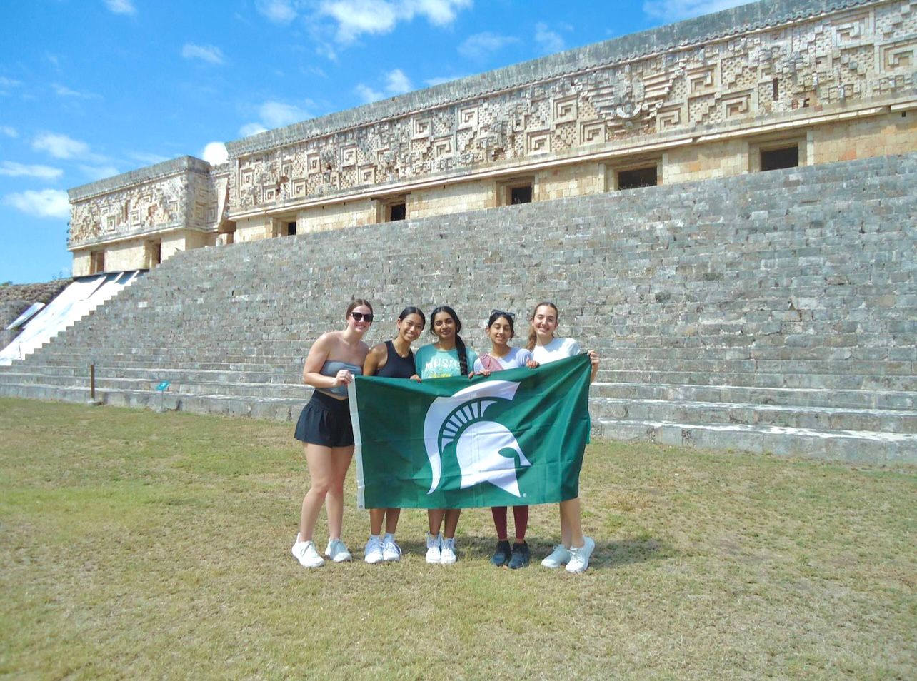 Maya and friends holding the Spartan flag in front of Mayan ruins