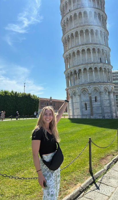 Abigail standing next to the Tower of Pisa looking like she's holding it up
