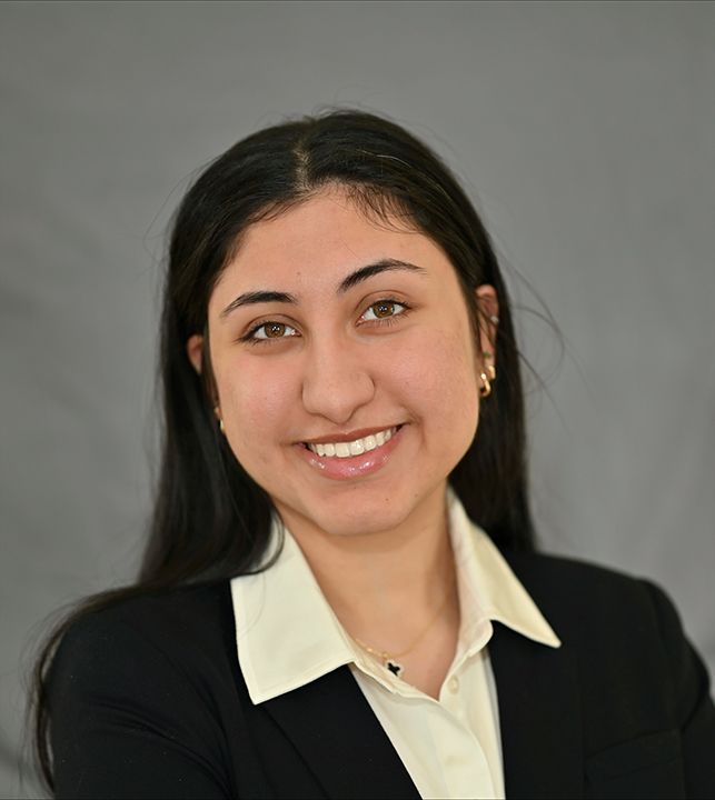 Nupur Huria smiling in a white shirt and black jacket.