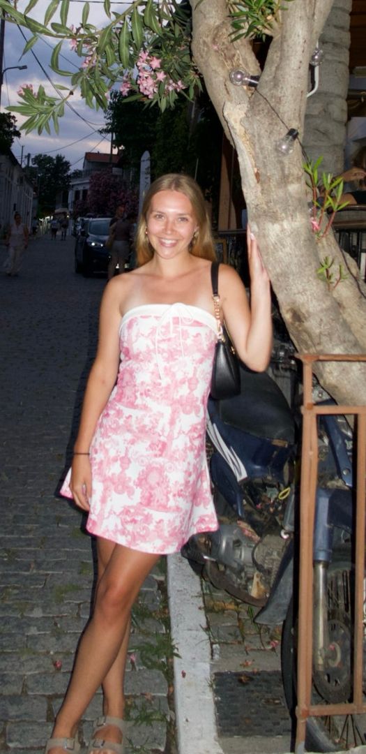 Brianna wearing a pink dress leaning on a tree 