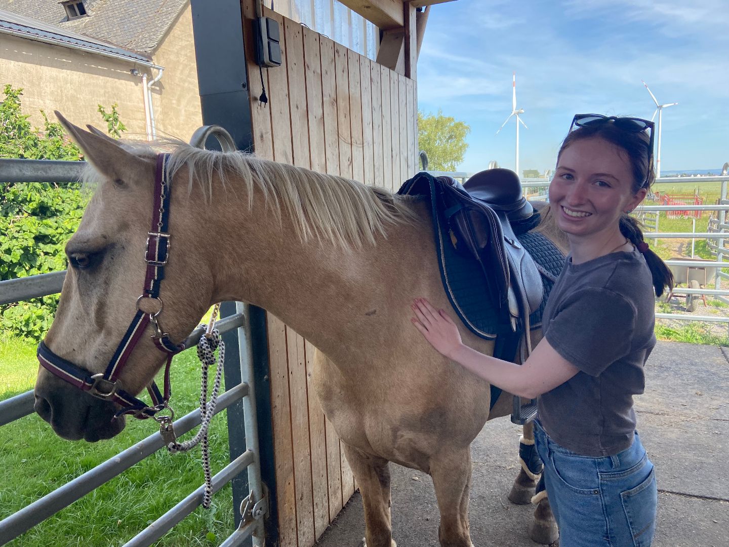 Ellie petting a tan-colored horse in Germany
