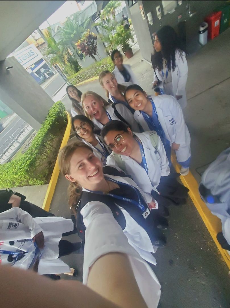 Group of students pose in white coats and scrubs