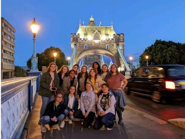 Group of students pose in front to Tower Bridge at night in London