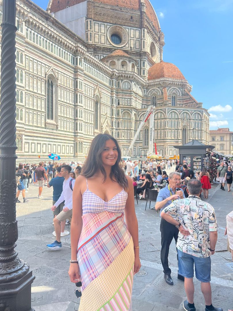 Lauren wearing a striped pink and purple dress in front of the Duomo in Florence