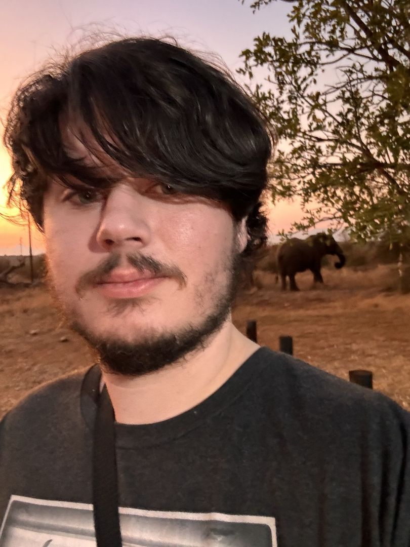 Ethan taking a selfie at sunrise/sunet with an elephant in the background