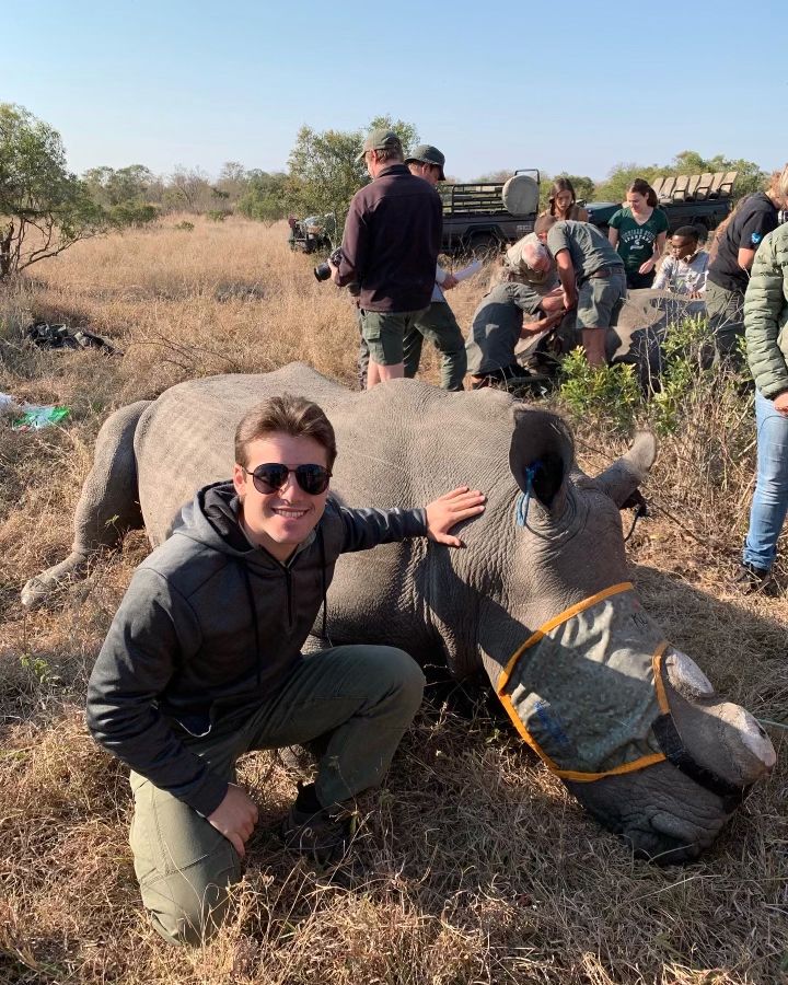 Bennett crouching next to captured rhino in South Africa