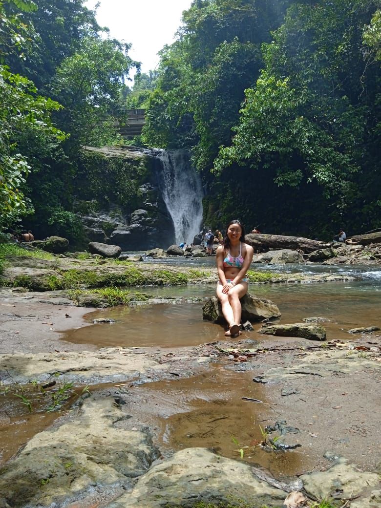 Waincey sitting on rock at the bottom of a waterfall in Costa Rica