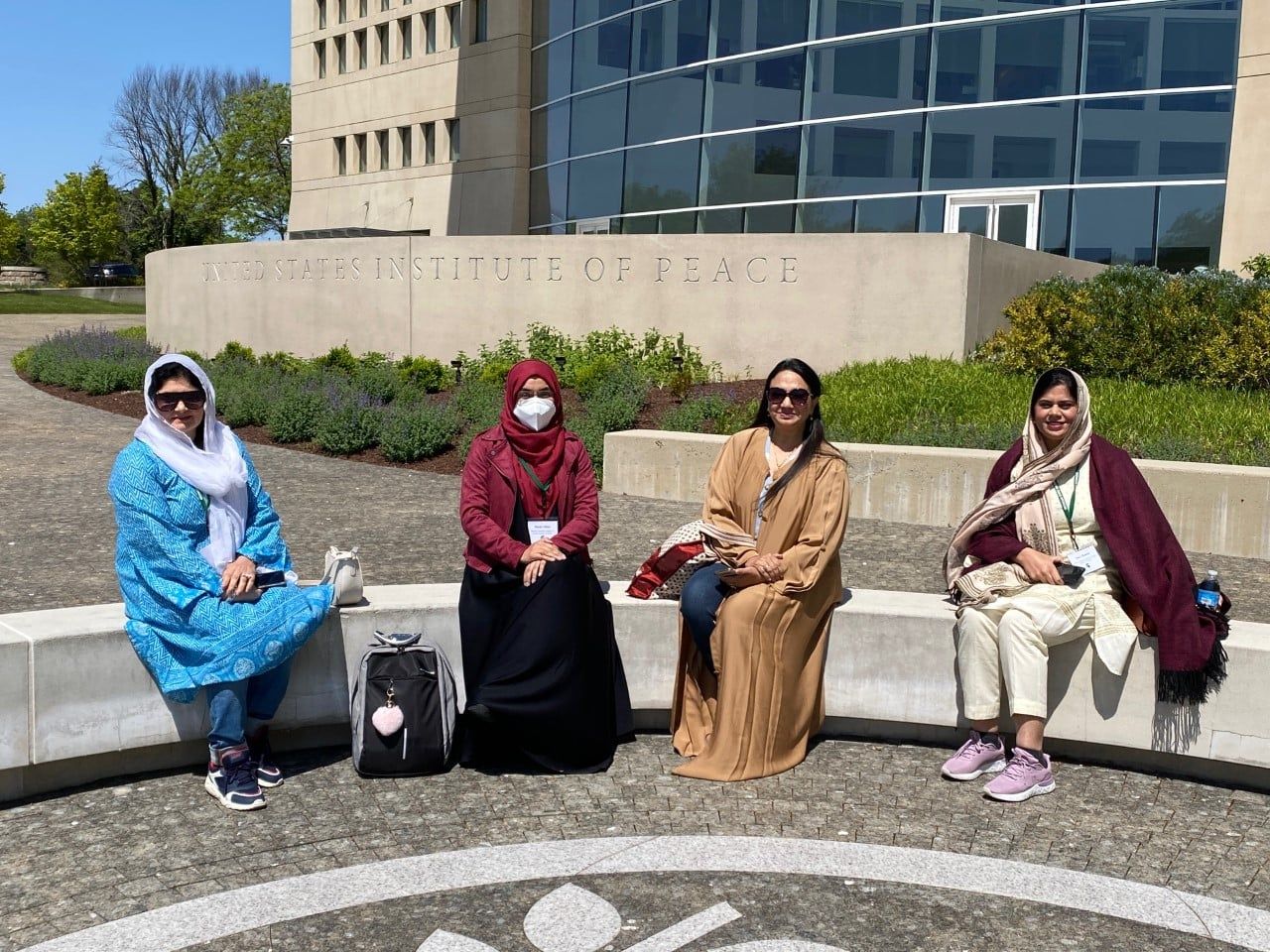 Four scholars sit in front of building