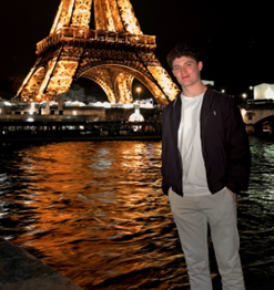 Sam standing in front of the Eiffel Tower in Paris at night