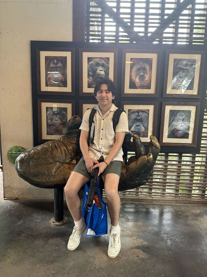 Adam sitting on a giant sculpture of a chimpanzee hand in Australia