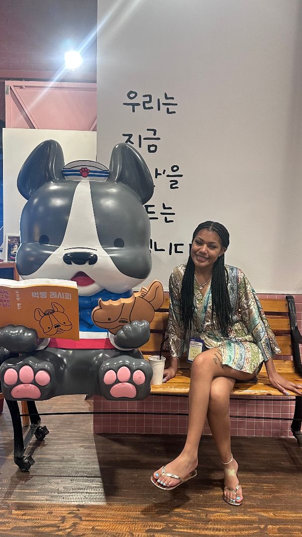 Quenita sitting on a bench next to a large character-like gray and white dog