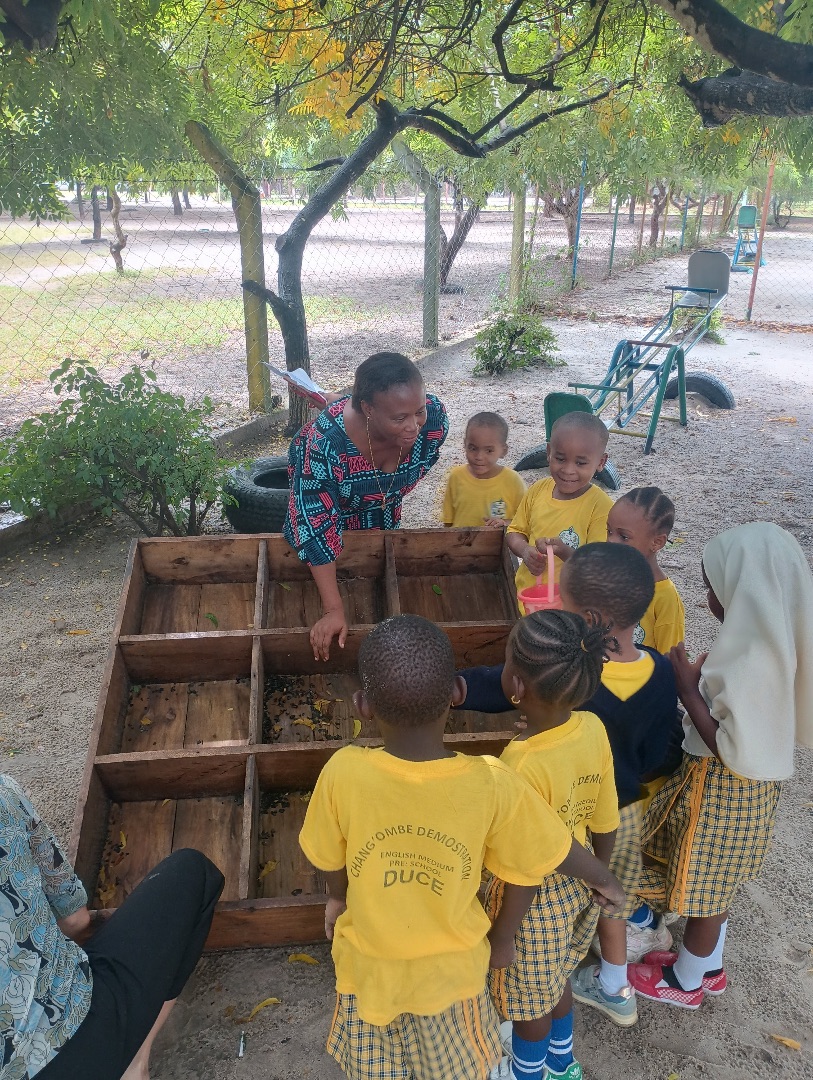 A woman supervises children in a learning activity outdoors