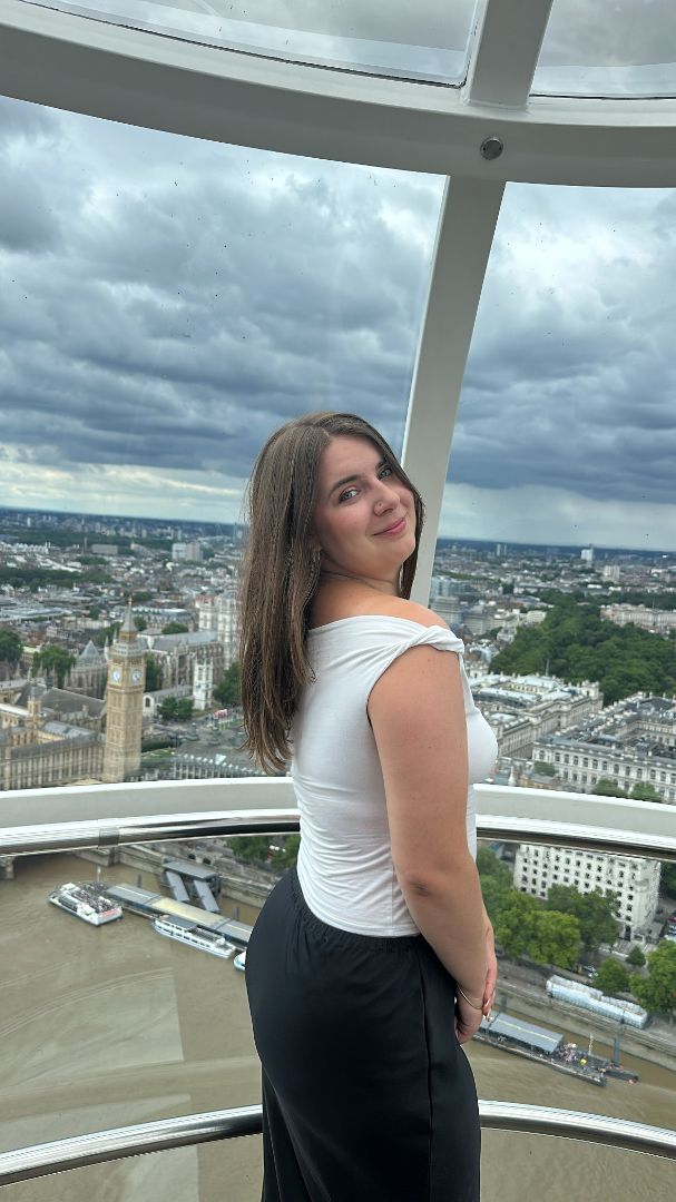 Alexandria wearing a white shirt and black skirt atop the London Eye