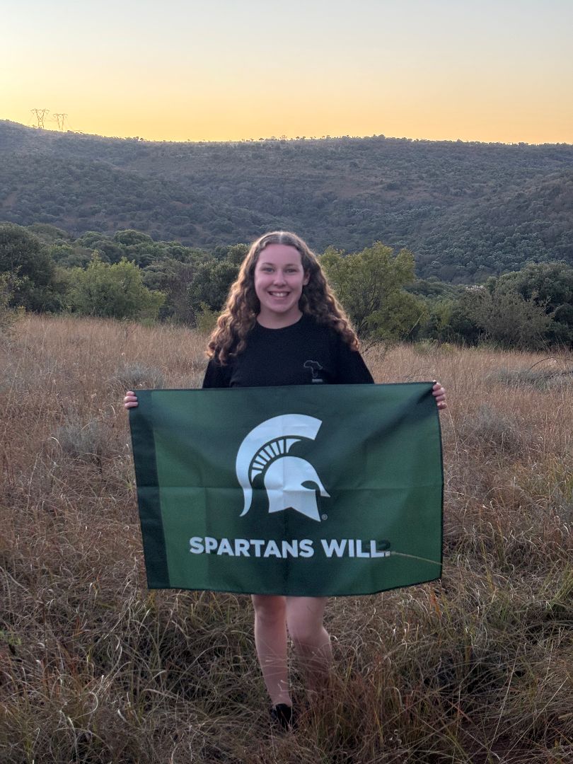 Megan holding a Spartan flag standing in the savannah