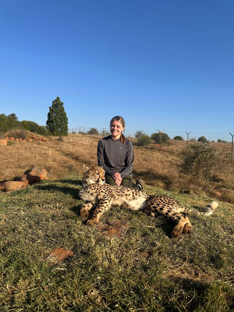 Skylar kneeling next to a cheetah