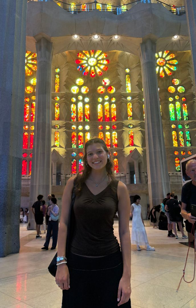 Victoria standing in front of the stained glass windows of the Sagrada Familia church