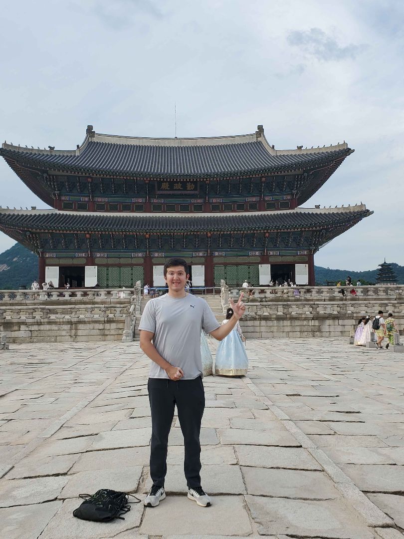 Julian standing in front of a large palace in Korea
