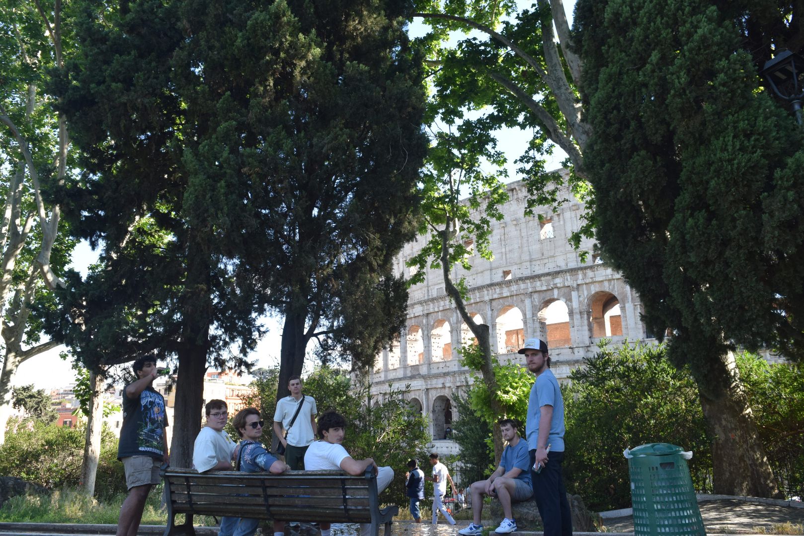 Reagan and friends sitting on a bench in the shade next to the Roman Colesium