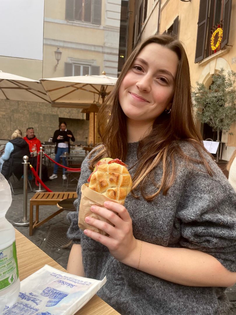 Amy holding a sandwich at a local cafe in italy