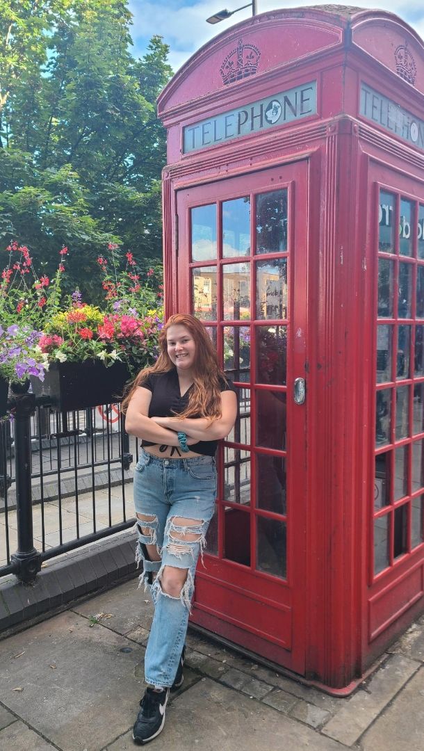 Shelby standing in front of an iconic red telephone booth in London