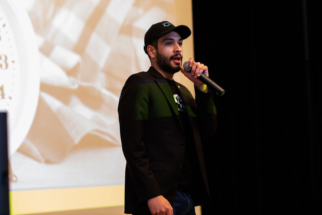 Founder of CAPIO stands before audience with mic in hand to pitch his product.