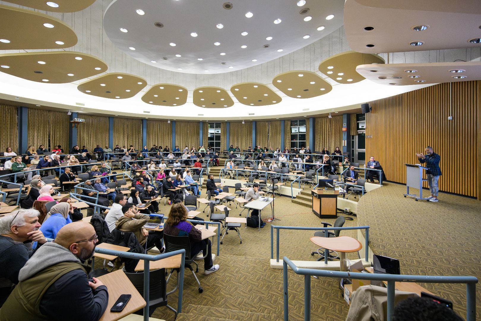 Wide view of Erickson Hall Kiva, filled with attendees.