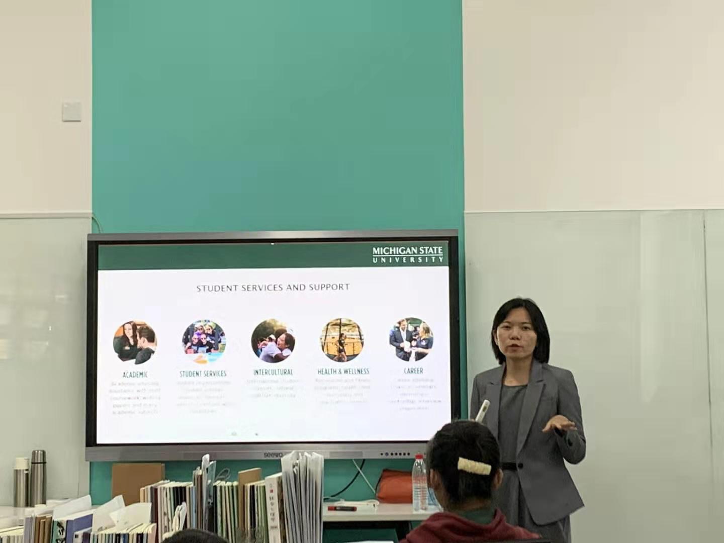 Jing presents about MSU in a classroom with a Power Point presentation beside her