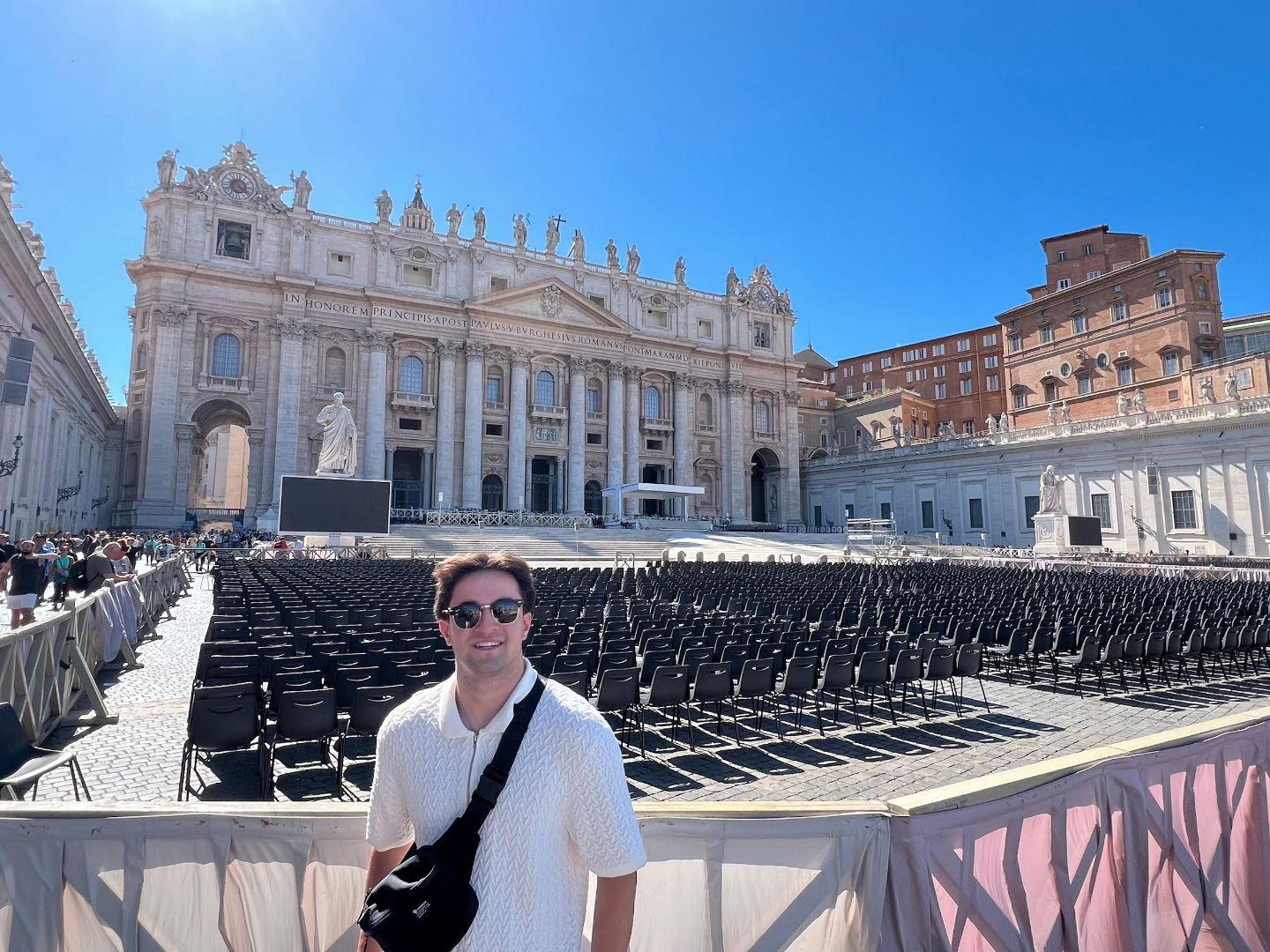 Andrew wearing a white shirt and sunglasses standing in front of St Peter's Basillica in Rome