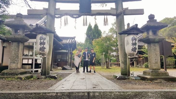 3 people standing under a torii gate at a shrine