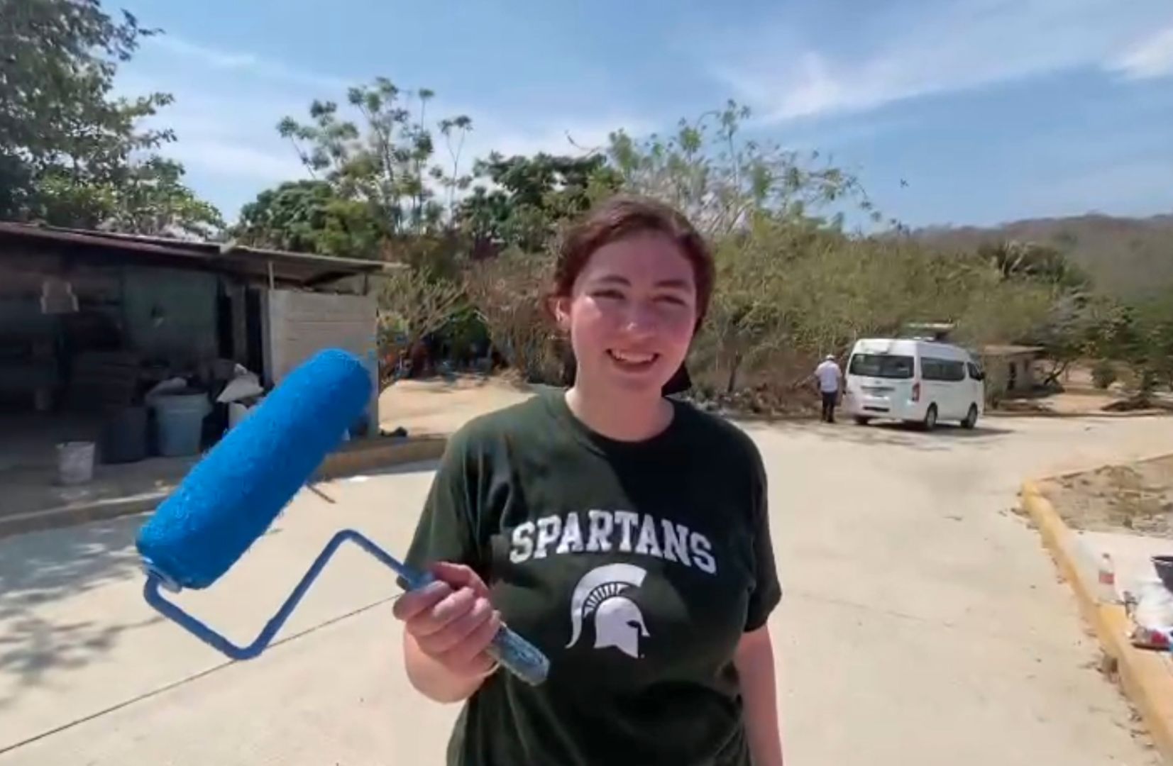 Chloe holding a paint roller wearing a spartan shirt