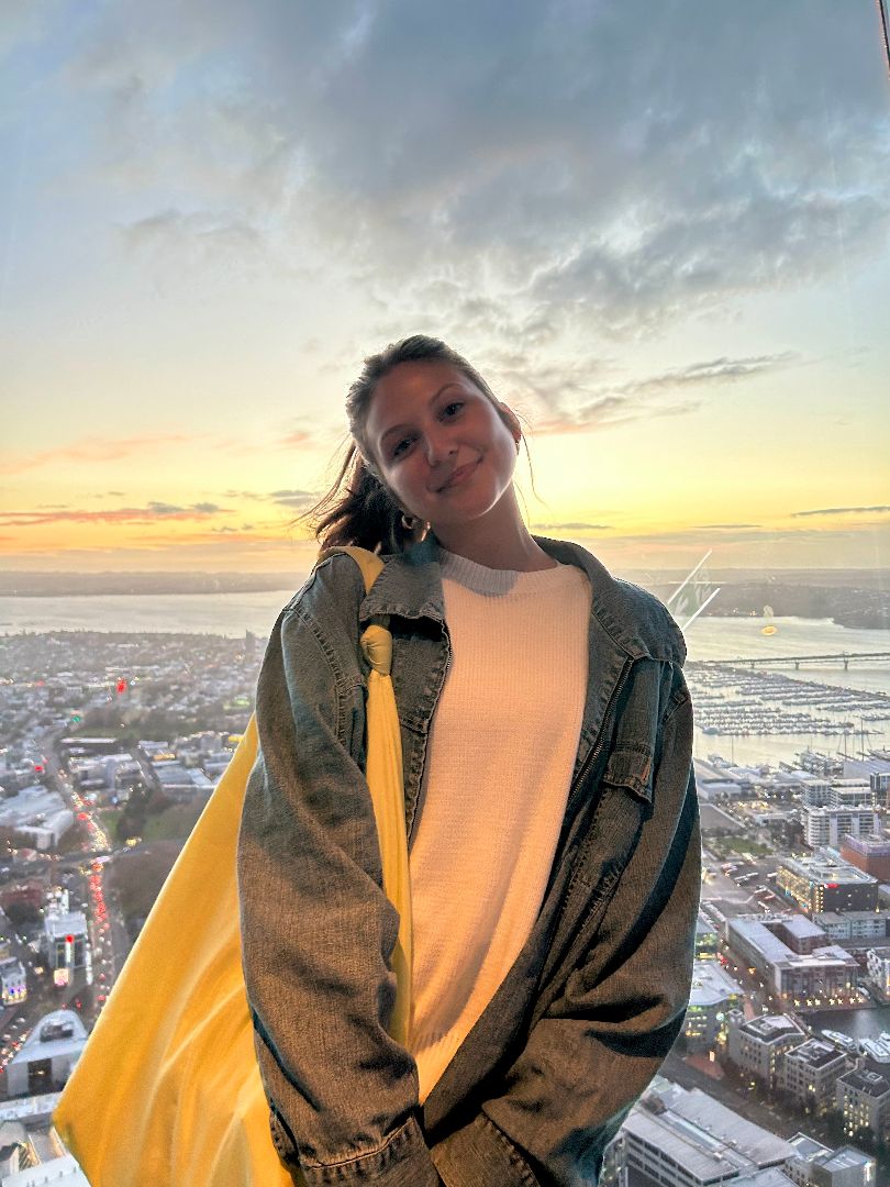 Stella with a yellow backpack standing high above a city in New Zealand