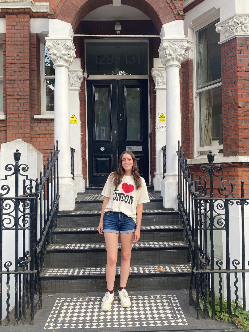 Abigail wearing an I love London tee shirt standing on the steps of a building with large white columns