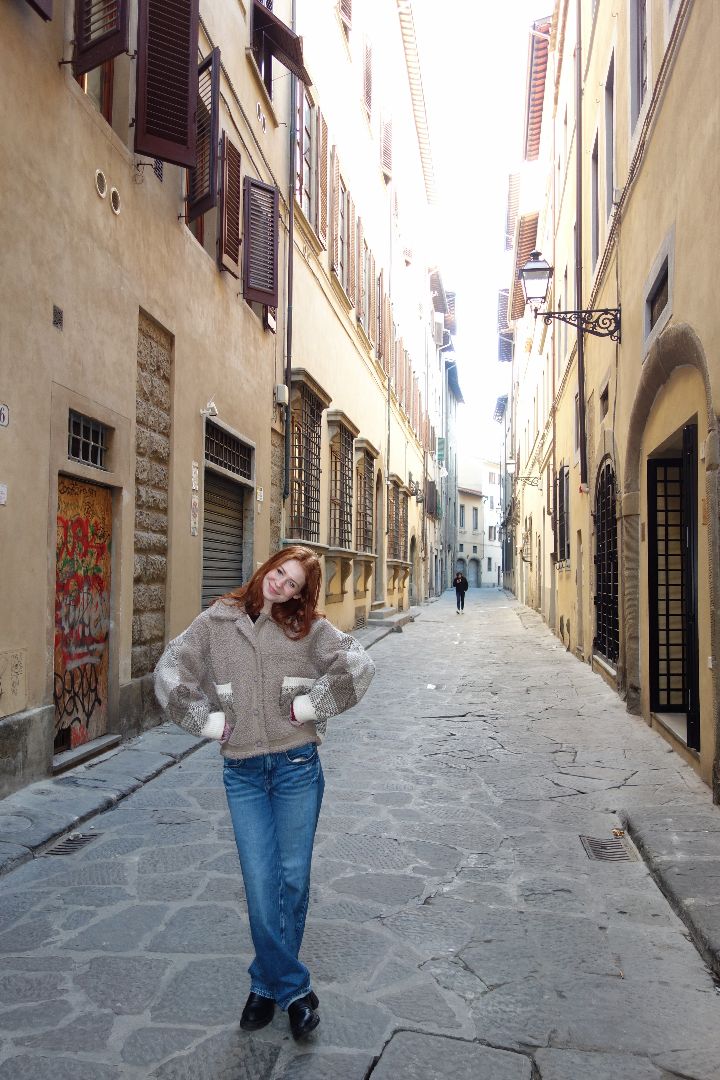 Greta posing for photo on a narrow cobblestone street in Italy