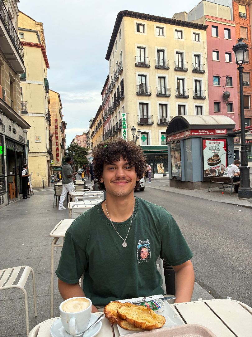Reuben eating a pastry in an outdoor cafe in spain