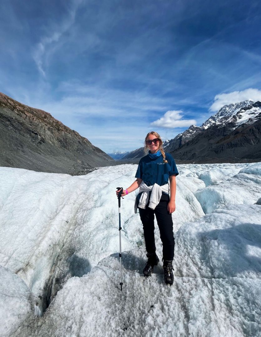 Vivian standing on a glacier in New Zealand holding a walking stick