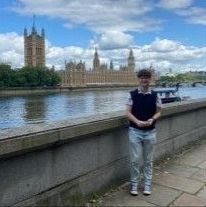 Finn standing by the River Thames with parliament in the background in London