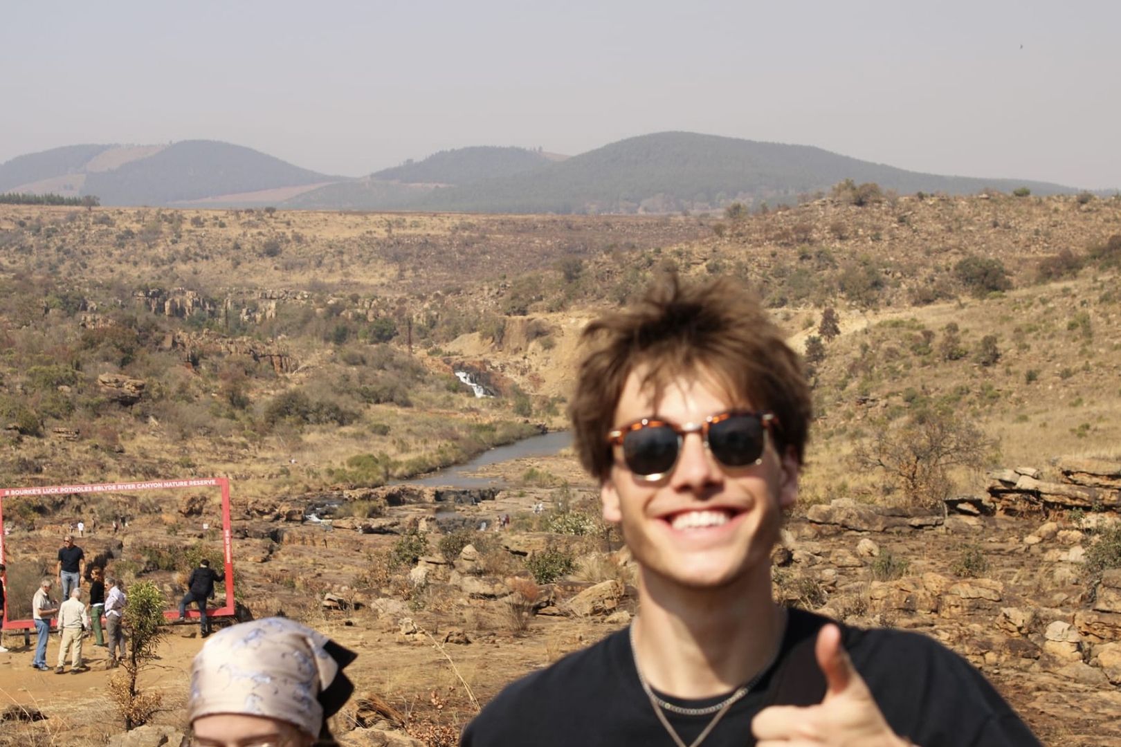 Adam giving a thumbs up wearing sunglasses while on the African savanah