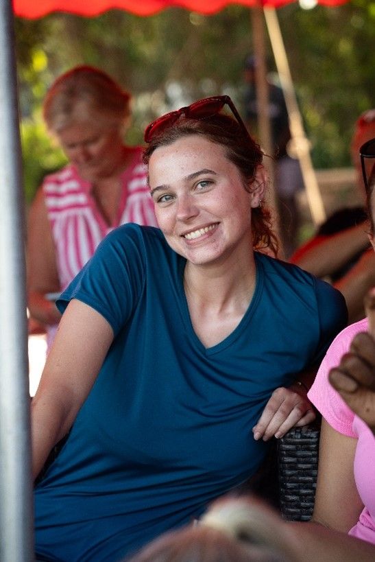 Erynn wearing a blue tee shirt leaning against a table in Fiji