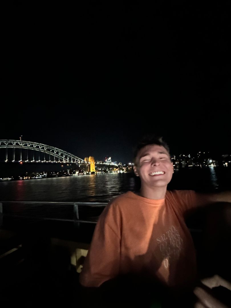 Benjamin posing in front of Harbor Bridge at night in Sydney