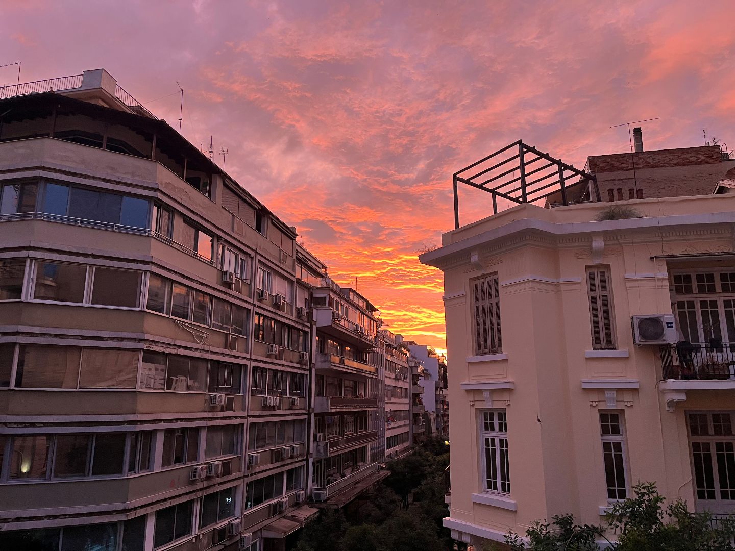 Two very different arcitecual buildings during a pink sunset
