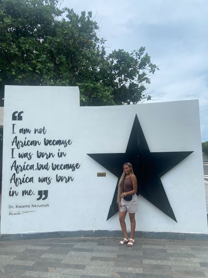 Danielle posing in front of a monument that reads I am not African because I was born in Africa but because Africa was born in me.