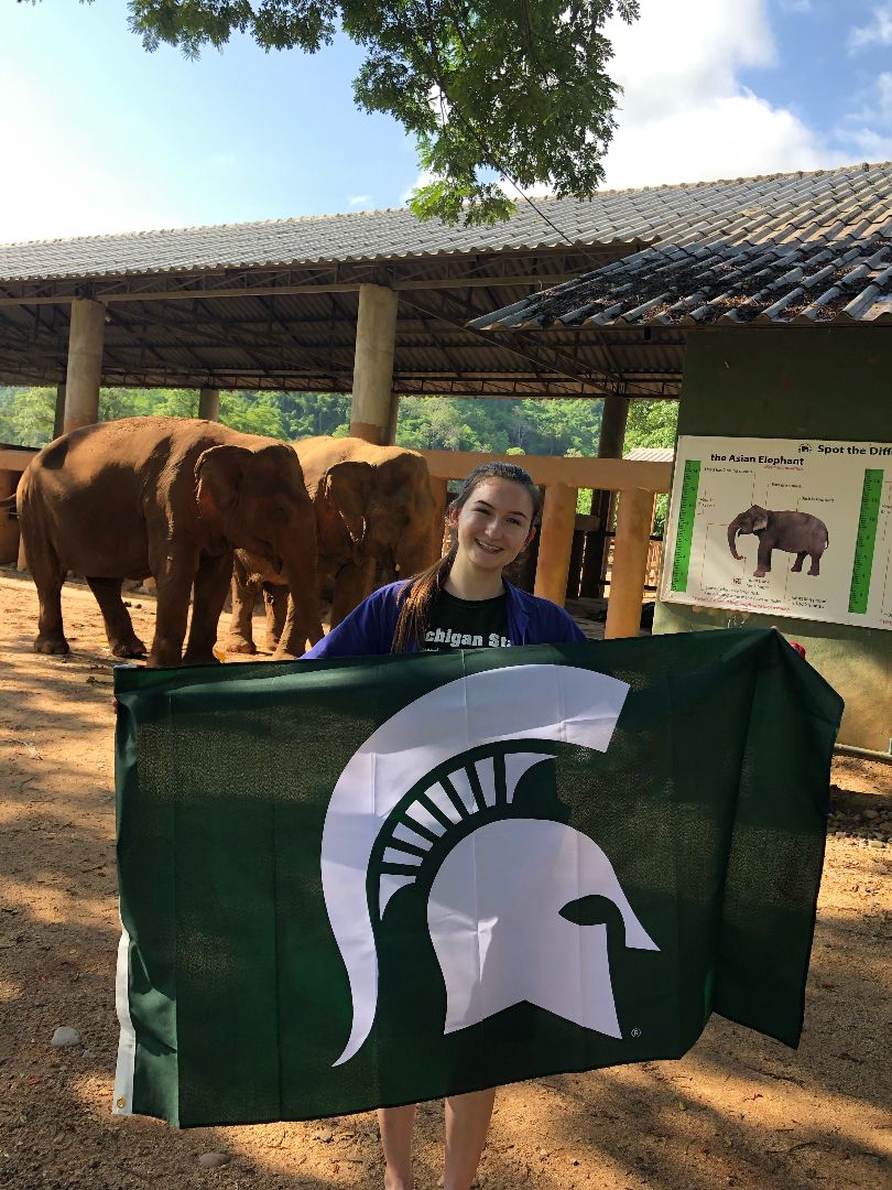 Anne holding Spartan flag by elephant in Thailand