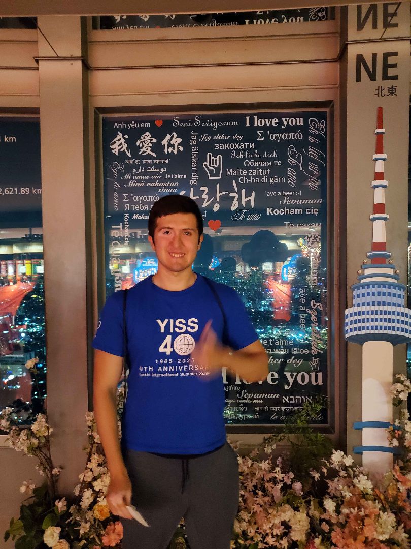 Julian wearing a blue shirt with a thumbs up at Seoul Tower