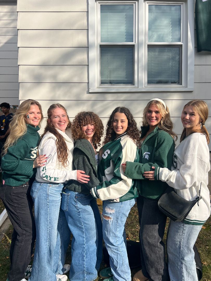 Renata posing with friends in MSU swag.