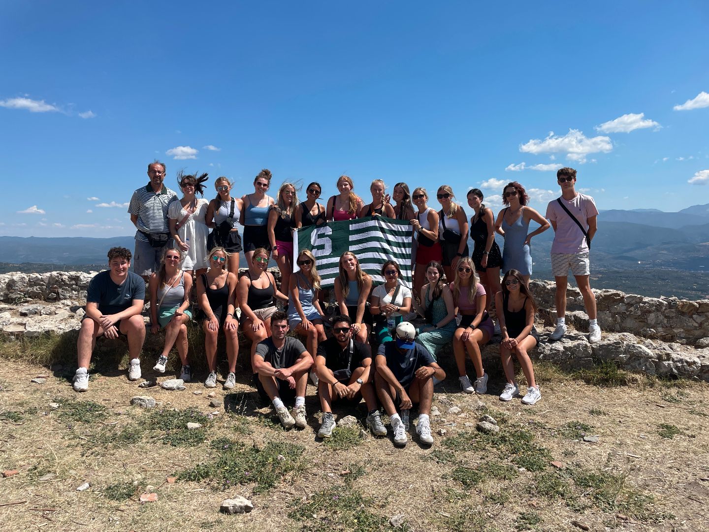 Group shot of students holding Spartan flag on top of a hill in Greece